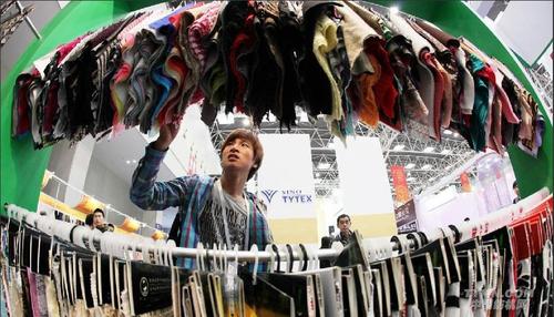 10月25日,客商在柯桥国际纺织品博览会展厅挑选面料
